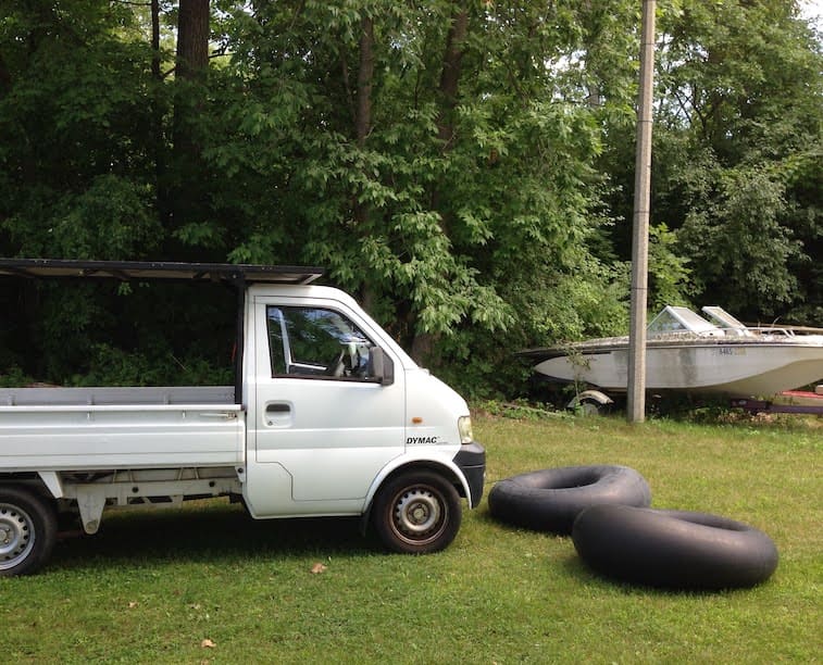 white pickup truck parked on green grass next to two giant inner tubes