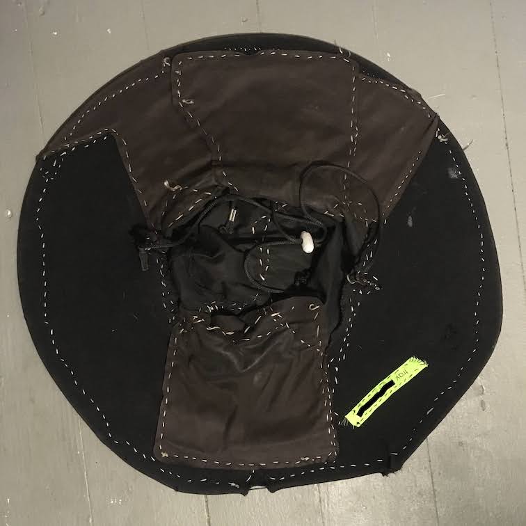 the bottom of the circular black hat showing white stitching and green label