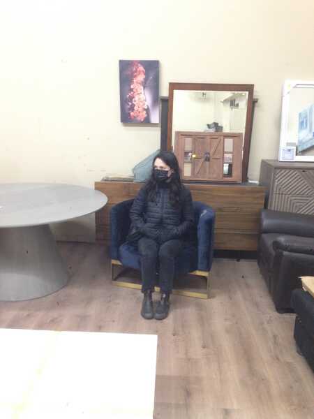 a woman in all black sits in a soft, blue chair